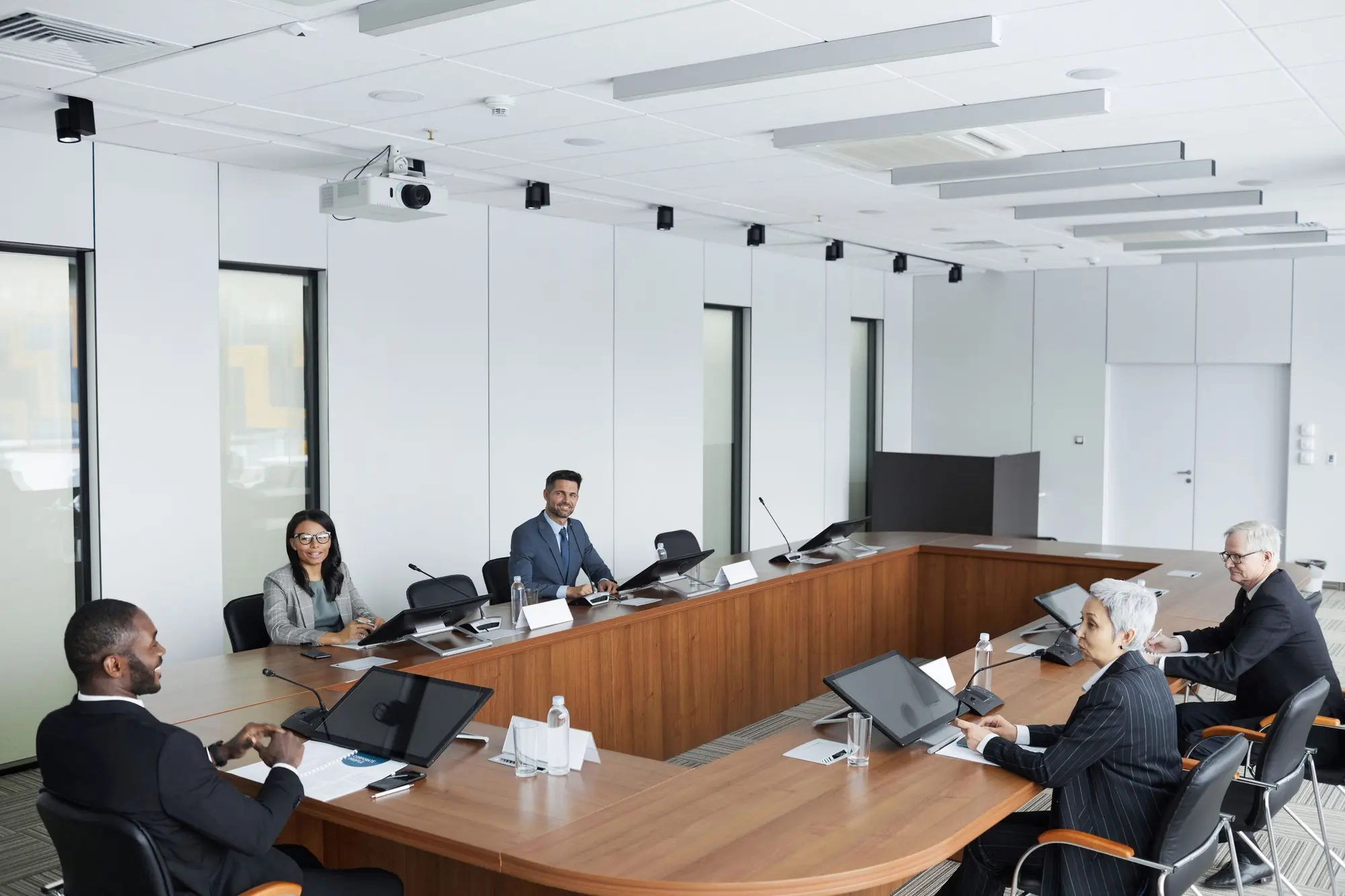 A diverse board of executives meeting around a U-shaped boardroom table