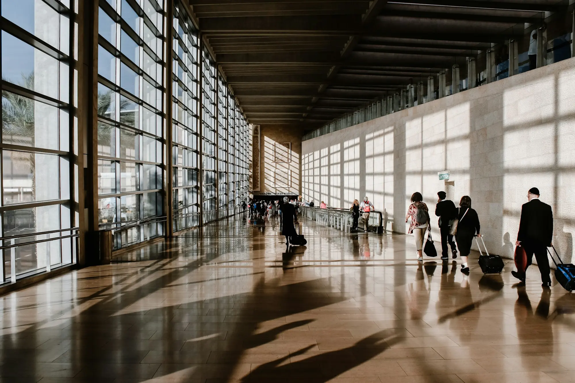 Travellers crossing a sunlit airport terminal